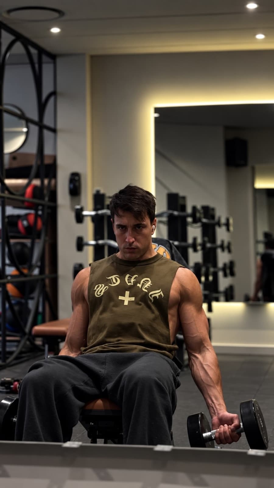 Tomás entrenando bíceps con musculosa Invictus